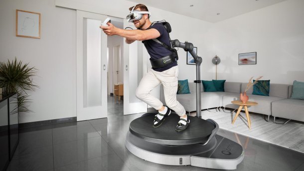 Ein Mann hält eine virtuelle Waffe und rennt auf Omni One mit VR-Brille.