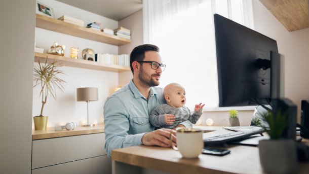 Mann im Home Office mit Kleinkind auf dem Schoß