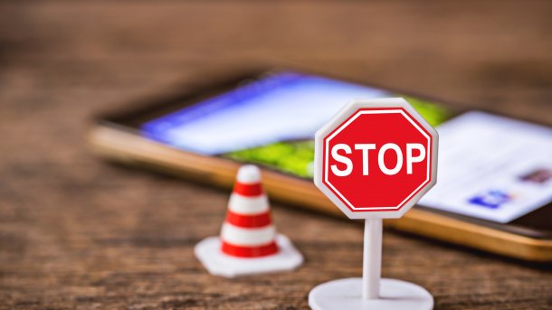 Stoppschild und Verkehrspylon vor verschwommenem Handy