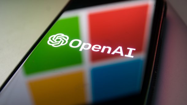 OpenAI-Logo auf dem Bildschirm eines Smartphones, in dem sich das Microsoft-Logo spiegelt