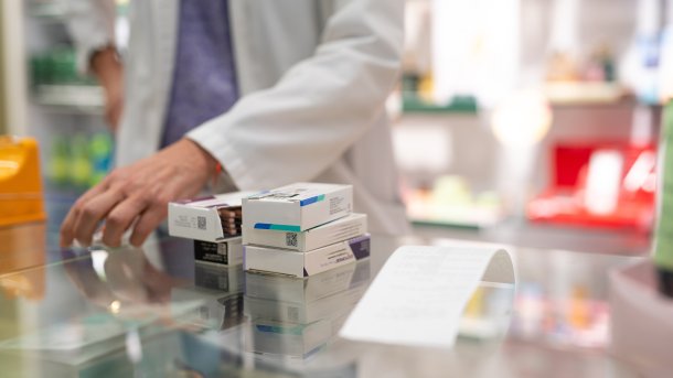 Medication in the pharmacy. Behind it a man in a white coat.