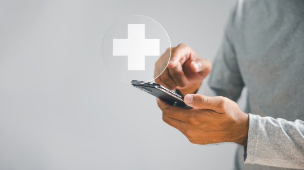 Man holds a smartphone. In the center is a white cross.