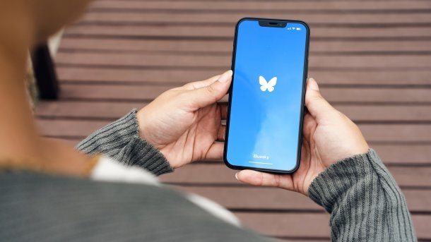 Person hält Handy in der Hand mit Bluesky-Logo