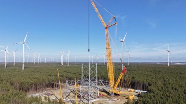 Construction site of the tall wind turbine in a forest area.