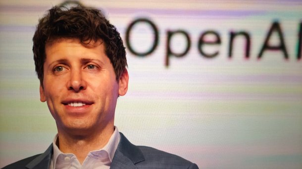 Sam Altman vor Leinwand mit OpenAI-Schriftzug.