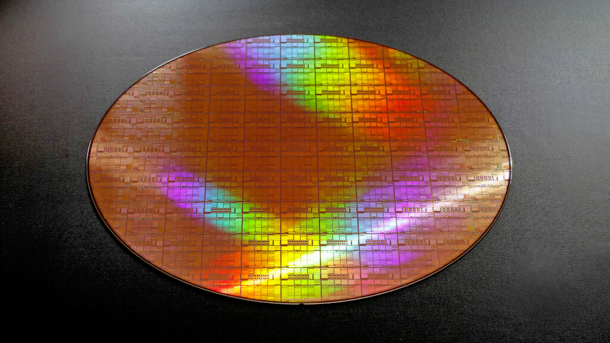 Ein bunt schimmernder 300-Millimeter-Wafer, die Silizumscheibe, auf der Dutzende Chips nebeneinander hergestellt werden.