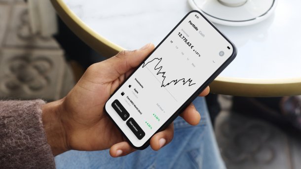 Hand hält Handy, auf dem Trade Republic läuft