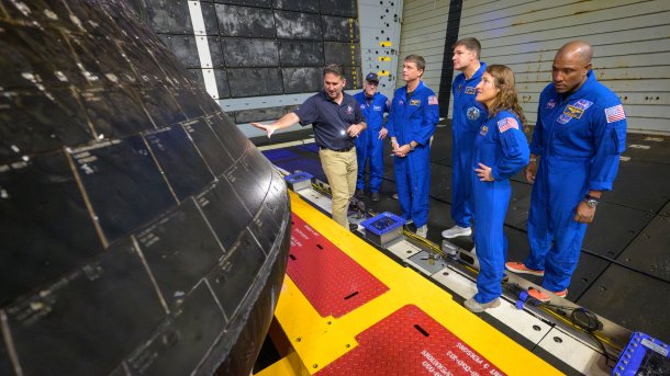 Links ein Stück der Orion-Kapsel, rechts die vier Raumfahrer