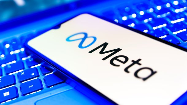 Meta logo and lettering on a smartphone lying on a keyboard.