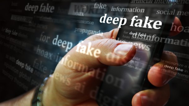 Deepfake-Schriftzug vor Handy in Menschenhand