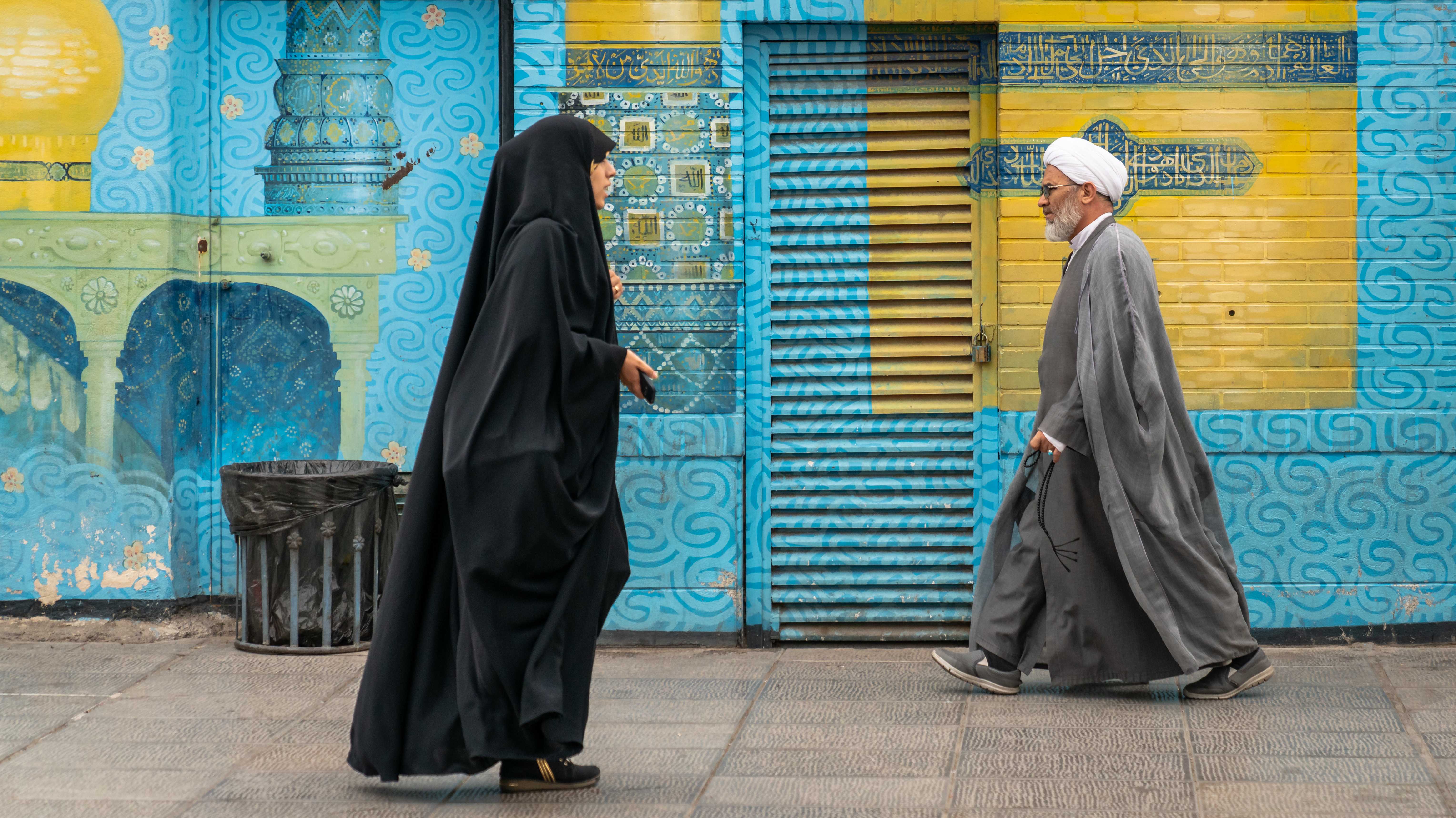 Iranischer Mann und Frau in schwarzem Kleid auf einer Straße in der heiligen Stadt Qom