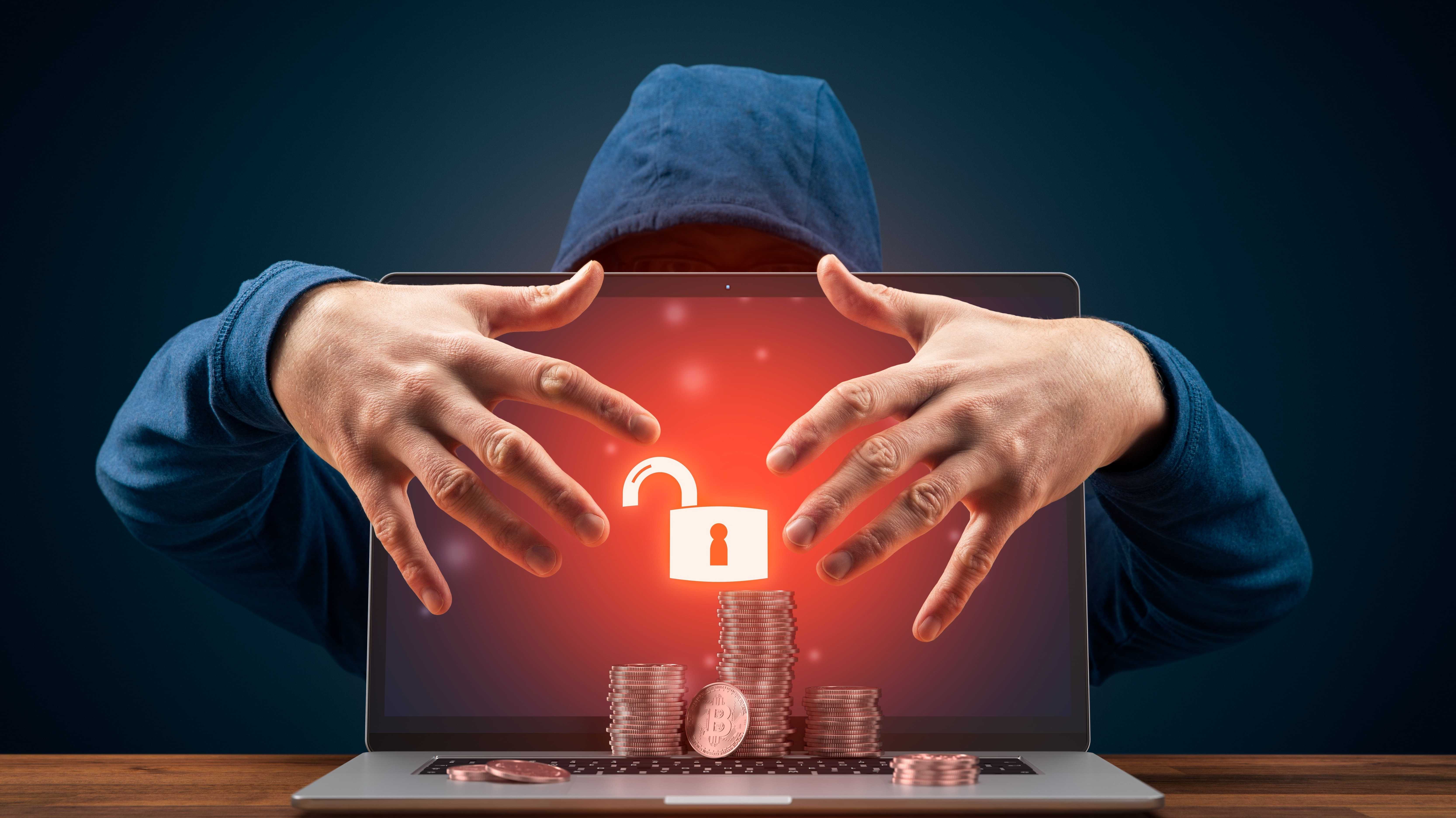 Symbolbild eines mensxchen mit verdecktem gesicht im Hoodie, der ein Bitcoins hackt