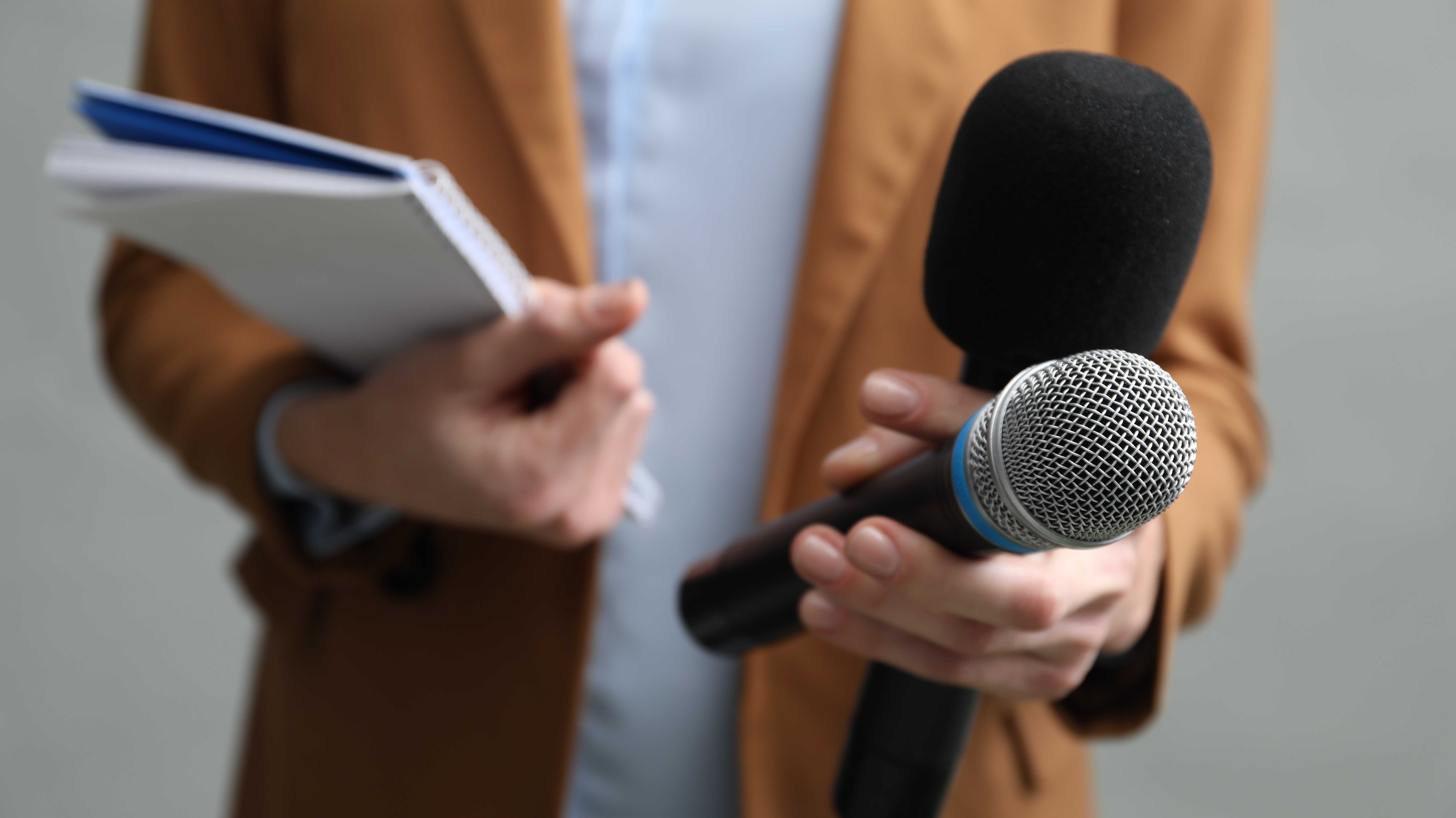 Reporterin mit Mikrofon, Schreibblock