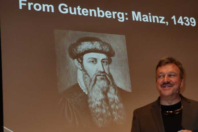 McCann im Vortrag vor Bild von Gutenberg