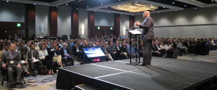 Anthony Foxx, auf Podium, hält Rede vor gefülltem Saal