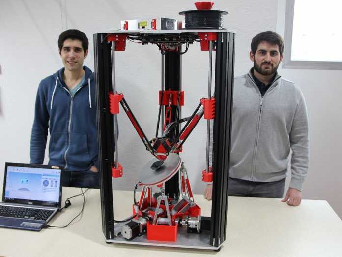 Zwei Studenten stehen neben einem meterhohen 3D-Drucker