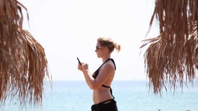 Frau am Strand mit Handy