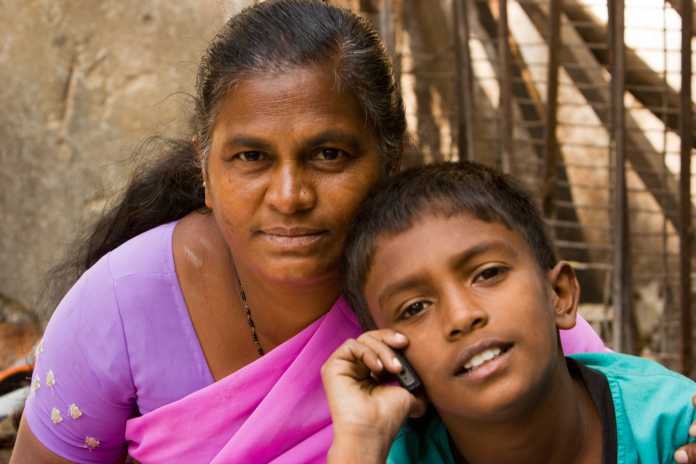 Indische Frau, davor Knabe, der mit Handy telefoniert