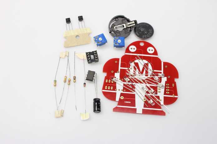 Löt-Makey: Eine rote Platine in Roboterform mit elektronischen Bauteilen