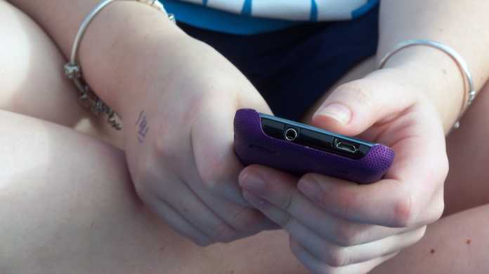 Hände eines Mädchens halten ein Handy