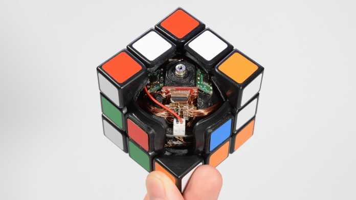Eine Hand hält einen geöffneten Zauberwürfel mit elektronischem Innenleben hoch