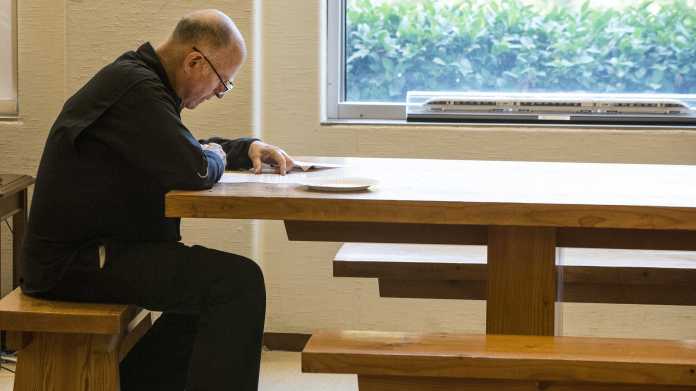 Jerry Brown lesend an Holztisch