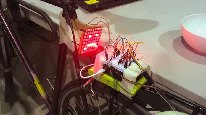 LED-Matrix mit Smiley und ein Breadboard-Aufbau mit vielen Kabeln auf Fahrradgepäckträger