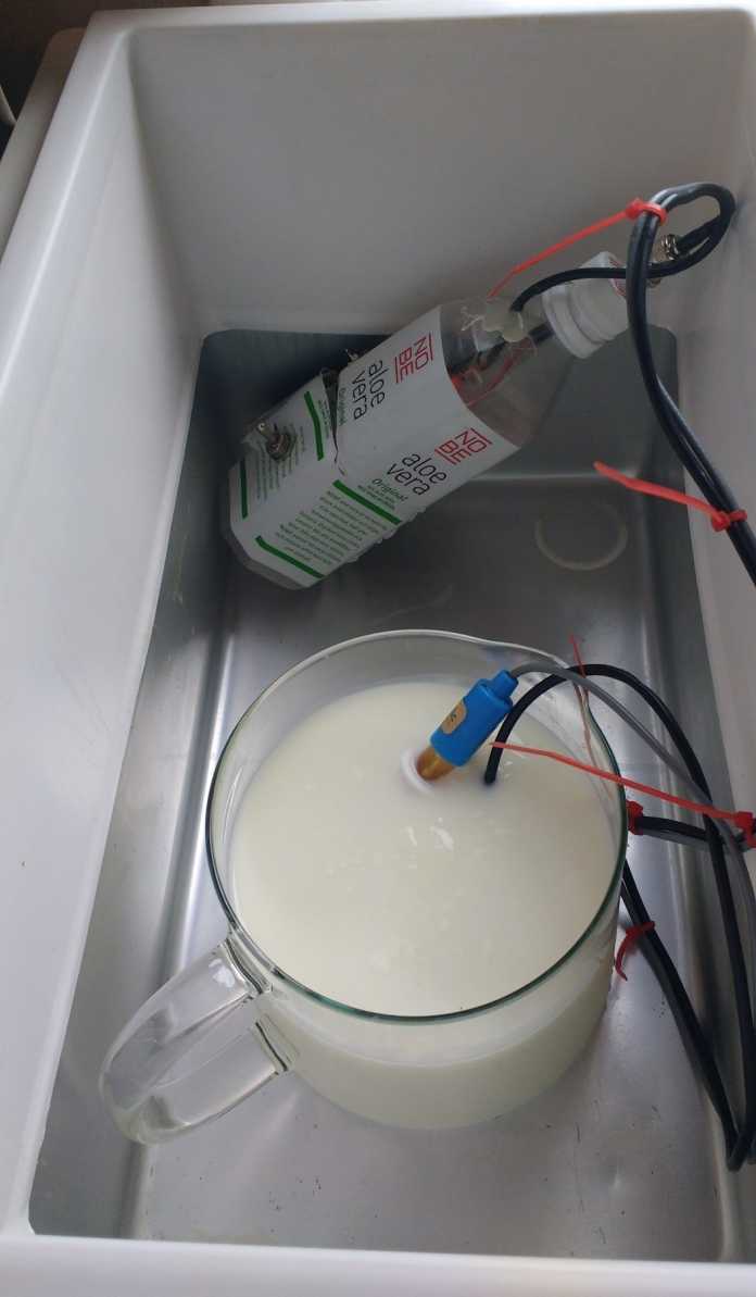 Blick in eine Kühlbox mit Milchkübel, in dem ein pH-Meter hängt.