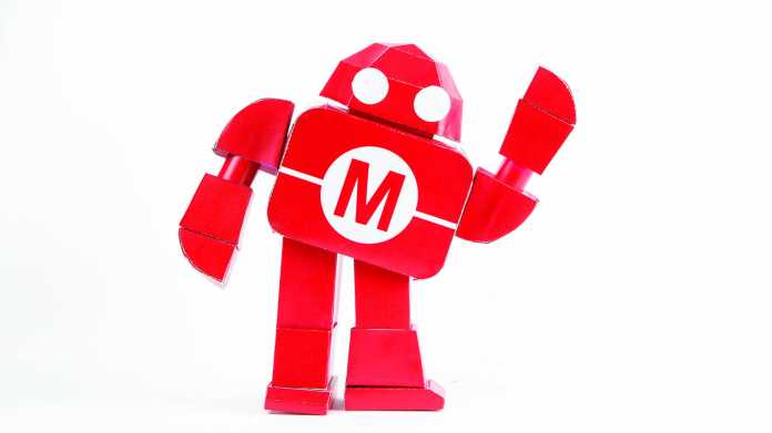Ein roter Roboter aus Pappe winkt.