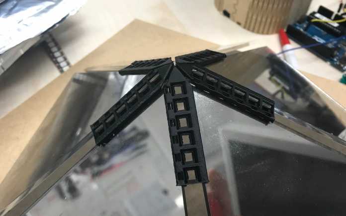 Auf einer Ecke von fünf Glasseiten sind fünf schwarze Streifen aus dem 3D-Drucker angebracht.