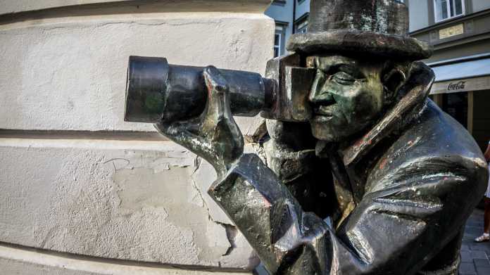 Bronzestatue lugt mit Teleobjektiv um eine Ecke