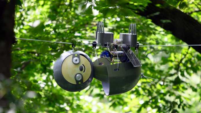 An einem Seil hängt ein Roboter mit rundem Kopf und rundem Körper, der Slothbot.