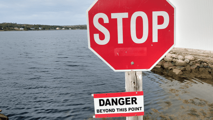 Stoptafel mit Zusatzschild "DANGER beyond this point" - dahinter Meereswasser