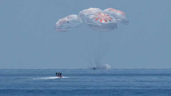 Kapsel mit 4 Fallschirmen knapp über dem Meer