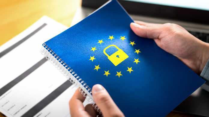 2 Hände halte ein blaues Heft worauf das Symbol der EU und ein gelbes Vorhängeschloss gedruckt sind