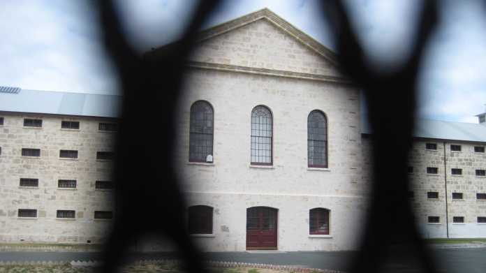 Gefängnisgebäude durch einen Metallzaun betrachtet