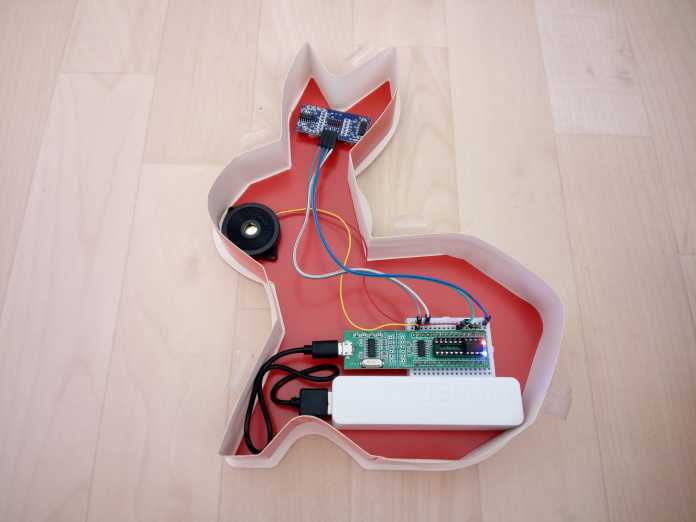 Eine Schokoverpackung, in der ein Ultraschallmodul, ein Lautsprecher und ein Steckbrett stecken.