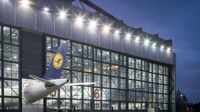 Ein Wartungshangar der Lufthansa-Werft in Hamburg: Der Airbus A340 ist zu lang für die Halle, das Flugzeugheck ragt bei geschlossenen Hallentoren durch eine spezielle Öffnung heraus. Die Belichtung orientiert sich an der Beleuchtung im Inneren der Halle, dadurch wird der Zweck des Hangars überhaupt erst sichtbar. Tagsüber reicht die Beleuchtung im Inneren nicht aus, der Hangar wirkt dann dunkel, denn zusätzlich versperren die spiegelnden Scheiben den Blick. Der blaue Nachthimmel passt hier ideal zum Logo am Leitwerk. Die Wahl einer kleinen Blendenöffnung erzeugt die Sterncheneffekte der Außenbeleuchtung.Canon EOS 5D Mark III  45 mm  ISO 200  f/11  2,5 s