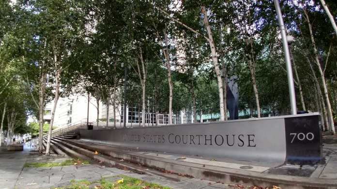 Schild "United States Courthouse", dahinter Bäume und ein Hochhaus