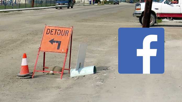 Schild "Detour" auf unbefestigter Straße - rechts danaben ein Facebook-Logo