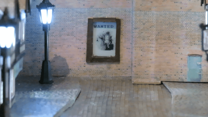 Ein Poster mit einem Gesicht und der Aufschrift &quot;Wanted&quot; hängt auf einer Wand in einer Modellbaugasse.