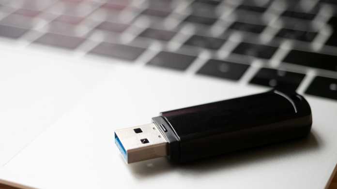 Ein USB-Stick liegt auf der Handballenauflage eines Laptops