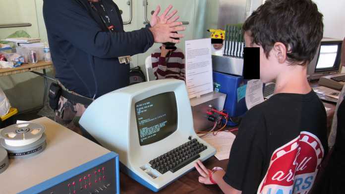 Alte Computer, drei Kinder - eines spielt ein Text Adventure Game