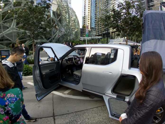 Ein Prototyp eines Rivian-Pickups steht ausgestellt mit offener Tür und Fronthaube vor der Amazon-Zentrale in Seattle