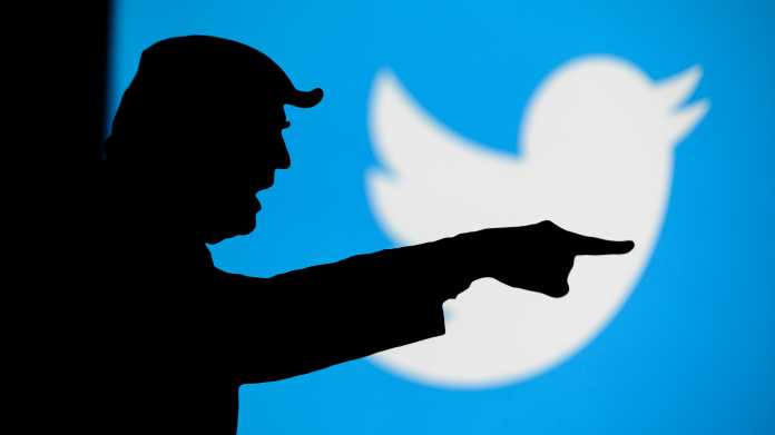 Schattenriss Donald Trumps mit ausgestrecktem Arm und Zeigefinger, dahinter das Twitter-Logo