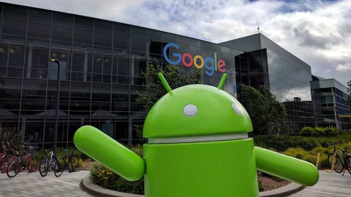 green android standing in front of google headquarters (glass building background)