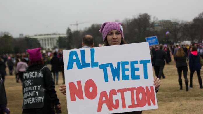 Frau hält Schild "All Tweet No Action"
