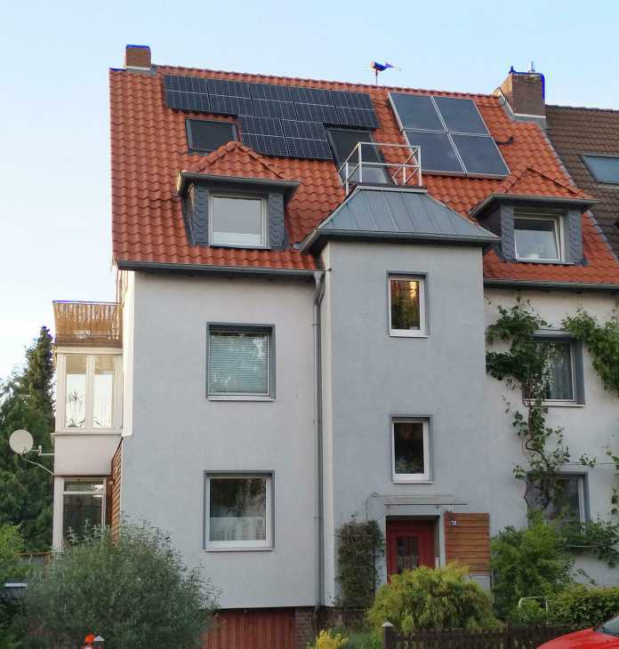 Ein Einfamilienhaus mit Vollbestückung: Außer einer Photovoltaikanlage liegen auf dem Dach auch noch Wärmetauscher für Solarthermie und im Hintergrund dreht sich ein kleines Windrad., Georg Schnurer