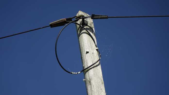 Spitze eines Leitungsmastes aus Holz mit gespannter Telefonleitung in Sehnde, Deutschland