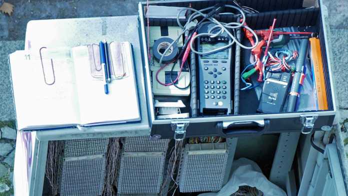 Werkzeugkoffer eines Telekommunikationstechnikers auf einem offenen Kabelverzweigergehäuse der Deutschen Telekom.